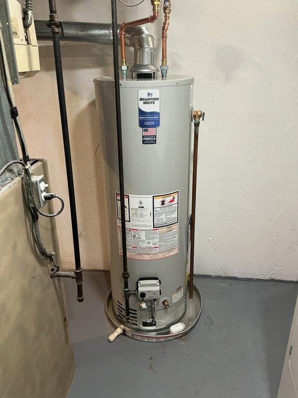 Completed warranty replacement of a damaged 40-gallon Bradford White tanked water heater. Removed and disposed of the dented unit, then installed new Bradford White 40-gallon gas-fired water heater in basement utility room. Connected copper supply lines with dielectric unions at hot and cold water connections, installed gas supply line with shut-off valve, and properly vented unit through existing ductwork. Installed temperature and pressure relief valve with discharge tube terminating near floor level per code requirements. System tested for proper operation, gas leaks, and water connections verified leak-free.