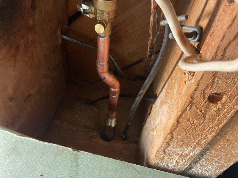 Coordinated with city utility department for water main shutoff to perform front foundation hose bib and water meter repairs. Accessed plumbing infrastructure through ceiling cavity, replacing damaged copper piping, brass valve assemblies, and associated fittings. Installed new hose bib connection with proper shutoff valves and reconnected meter assembly using code-compliant copper and PVC pipe transitions within wooden framing structure.