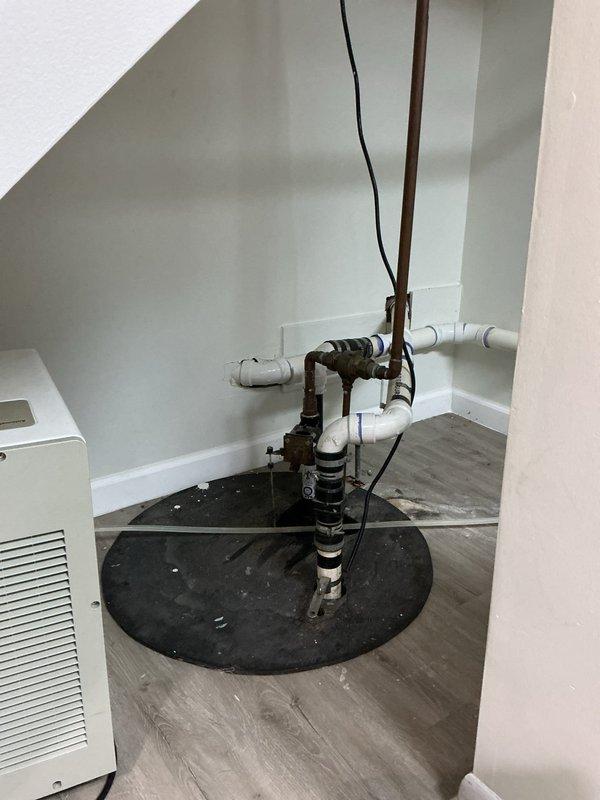 Responded to service call regarding sump pump overflow line malfunction and replacement evaluation. Upon arrival, inspected existing sump pump installation in utility room, including discharge piping configuration and overflow line routing. Assessed PVC discharge pipe assembly and identified issues with overflow line water flow direction. Examined pump basin, check valve operation, and piping connections to determine system deficiencies. Documented existing plumbing infrastructure including copper and PVC pipe configuration, electrical wiring, and pump mounting setup. Provided comprehensive assessment of sump pump system and prepared replacement quote for customer consideration.