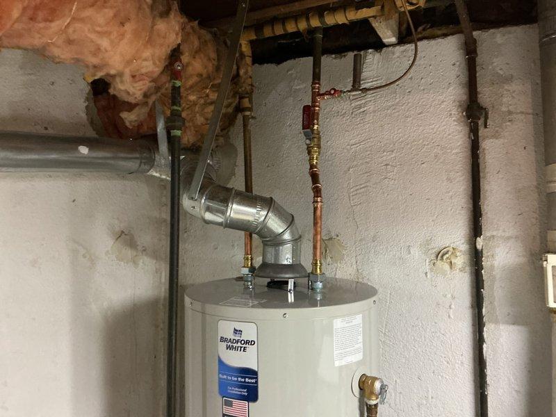 Responded to service call for water heater leaking from bottom in basement utility area. Upon inspection, determined existing Lochinvar unit had failed tank integrity and required full replacement. Removed old water heater and disconnected all plumbing connections and venting. Installed new Bradford White tanked water heater with proper venting through existing exhaust system. Connected copper supply lines, installed new shutoff valves, and ensured all connections were secure and leak-free. Tested unit for proper operation, verified temperature and pressure relief valve functionality, and confirmed no leaks at any connection points. System restored to full operation.
