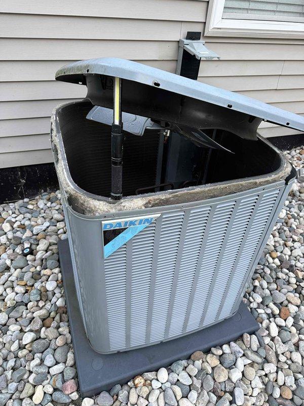 Responded to service call for AC system not cooling to setpoint, with indoor temperature at 80°F while thermostat set to 75°F. Upon arrival, checked in at security gate and accessed 6-year-old Daikin outdoor condensing unit located at rear of property on decorative rock bed against building exterior. Opened top panel and performed diagnostic inspection of internal components. System was blowing cool air but failing to reach desired temperature. Completed troubleshooting procedures and necessary repairs to restore proper cooling operation and temperature control functionality.