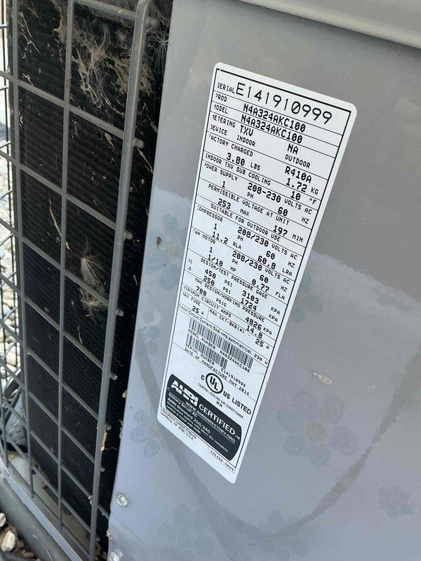 Completed comprehensive Gold AC Inspection and annual tune-up on residential cooling system. Inspected outdoor condenser unit (Model N4A324AKC100, R-410A refrigerant, 208-230V) located on concrete pad with proper gravel clearance. Verified all electrical connections at disconnect box and wall-mounted components, confirmed unit nameplate specifications and serial number documentation, cleaned condenser coil fins, checked refrigerant levels, tested capacitor performance, and verified proper fan motor operation. System operating within normal parameters with no deficiencies noted; unit shows appropriate weathering for age with all safety components functioning correctly.