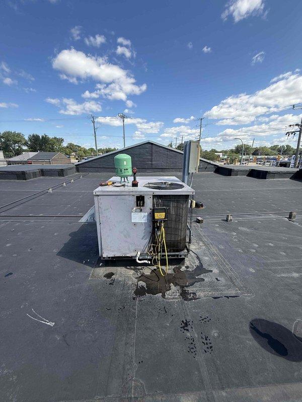 Responded to report of water dripping inside building from rooftop HVAC unit. Inspected commercial air conditioning system and confirmed unit was operating properly with adequate cooling performance. Conducted thorough examination of rooftop unit, refrigerant lines, and drainage components to identify source of interior water leak and documented equipment condition with photographs.