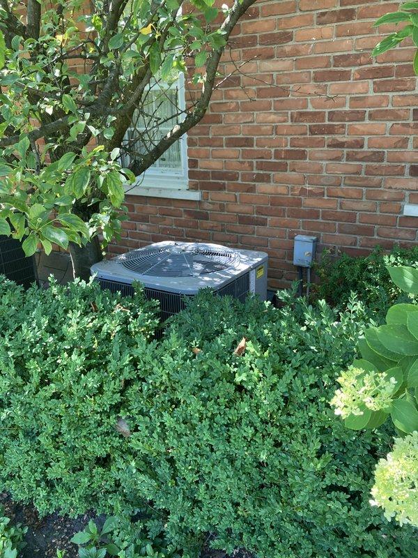 Completed estimate for replacement of 5-year-old residential air conditioning system with outdoor condensing unit currently located against brick exterior wall in landscaped area. Assessed existing equipment condition, verified electrical connections and concrete pad placement, documented current installation configuration including proximity to building structure and surrounding vegetation. Provided comprehensive replacement options and specifications for new HVAC system to meet homeowner's cooling requirements.