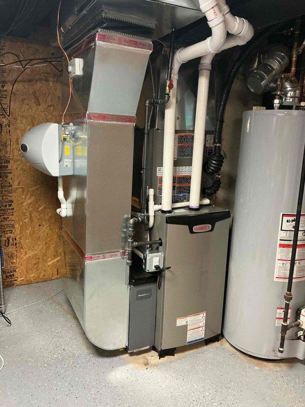 Completed full HVAC system installation including 70,000 BTU furnace, 2-ton air conditioning unit with rear discharge configuration, and humidifier in residential basement utility area. Installed low-profile condensate pump, reconnected electrical service at main panel, and coordinated mechanical and electrical permit requirements. UV light system requires transformer installation by electrician to complete project, with all ductwork connections, PVC condensate lines, and copper refrigerant lines properly installed and secured.