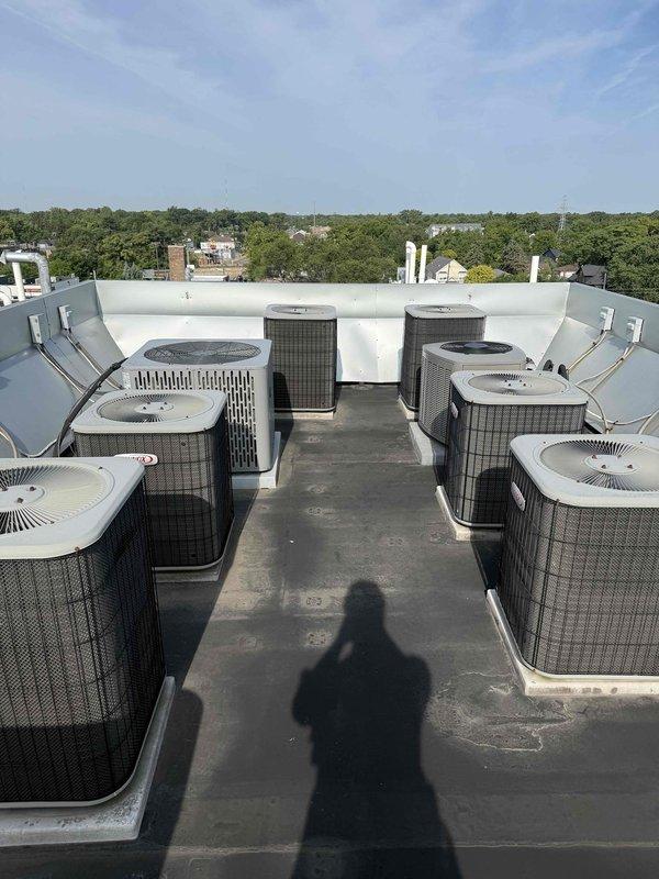 Responded to service call for 20-year-old rooftop A/C unit running but not cooling adequately. Accessed rooftop equipment via internal ladder and performed diagnostic evaluation of the affected condenser unit. Upon inspection, identified and addressed cooling performance issues on the unit with the white and beige housing featuring circular fan grille. Verified proper operation of condenser fan motor, checked refrigerant lines for restrictions, and assessed overall system performance. Restored unit to proper cooling operation and confirmed adequate airflow throughout the system.