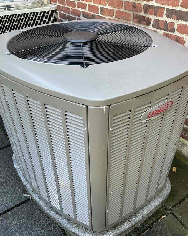 Completed comprehensive Gold AC Inspection on multi-unit residential HVAC system consisting of two outdoor condensing units: one Lennox unit and one Bryant unit, both positioned on exterior concrete pads against brick wall. Performed thorough visual inspection of both condenser units, evaluated physical condition of cabinets showing normal outdoor weathering, verified proper installation on concrete pads, inspected fan guards and louvers for adequate airflow, checked refrigerant labels (Puron), and documented equipment specifications. Noted minor organic growth accumulation around unit bases and dirt buildup consistent with outdoor exposure, though both units remain operational. Equipment located at basement and side of house positions, with upstairs unit being newer installation. All components inspected and photographed for maintenance records.