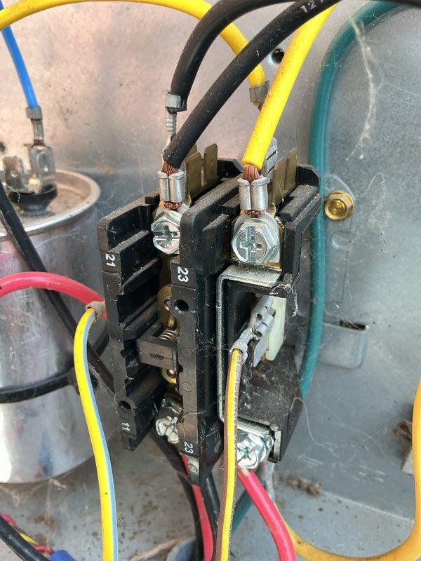 Completed comprehensive Gold AC inspection on residential property with two outdoor condenser units and multiple indoor units including attic-mounted air handler and basement boiler system. Performed visual inspection of both outdoor condensers positioned on concrete pad, confirming units in good operational condition with clean fan grilles, intact protective guards, and no visible damage or deterioration to exterior components. Inspected electrical contactor assembly, verifying proper wire connections across all phases with yellow, black, red, and blue conductors securely terminated at contact blocks. Documented system configuration with mini-split components distributed throughout home. All equipment confirmed operational at time of inspection with no immediate service needs identified.