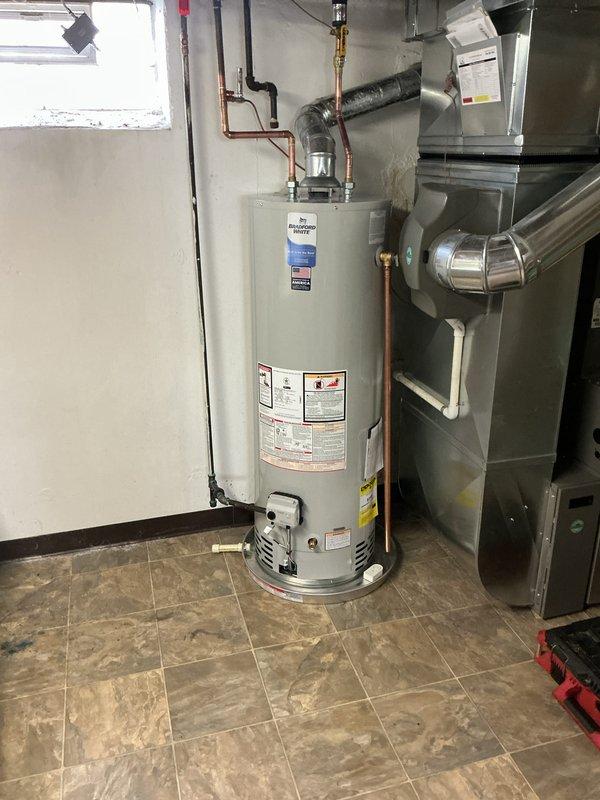 Completed installation of 40-gallon tanked water heater in basement utility area with proper copper piping connections and venting. Customer was advised that a drain pan is required per code compliance to prevent potential violations, and this item needs to be installed to meet current plumbing regulations.
