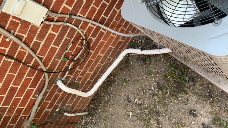 Responded to no cooling complaint on 4-year-old residential air conditioning system located in backyard. Upon arrival, performed diagnostic inspection of outdoor condensing unit and associated refrigerant lines. Verified electrical connections at disconnect box, inspected condenser coil condition, and checked refrigerant line insulation integrity. Unit appeared to be in normal operating condition with proper installation of PVC refrigerant lines and electrical components properly secured.