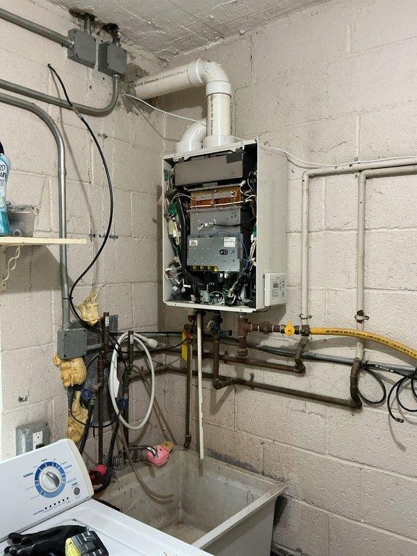 Removed existing wall-mounted tankless water heater unit and successfully installed a new 40-gallon standard tank water heater in the utility room. Disconnected and capped PVC exhaust venting system that was previously required for tankless operation. Reconnected existing copper water supply lines, gas line, and electrical connections to new tank unit per manufacturer specifications and local code requirements.