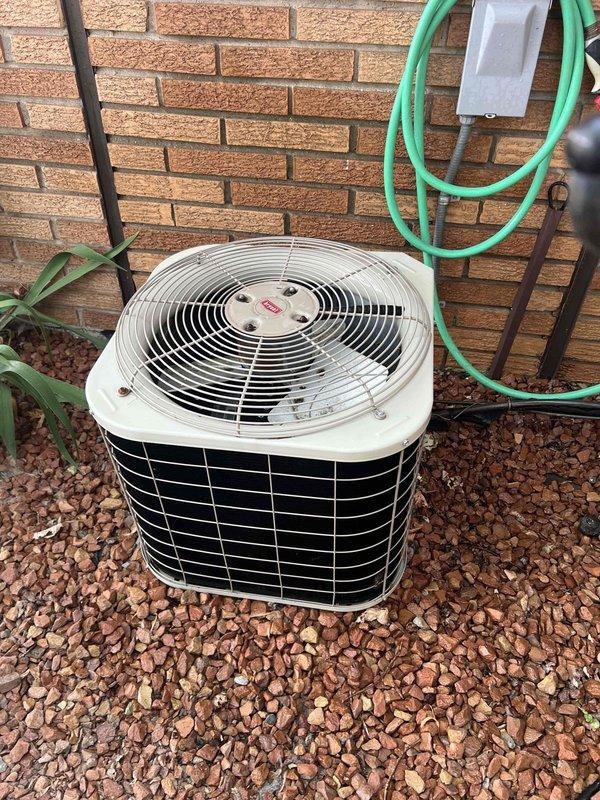 Performed comprehensive Gold Plan maintenance inspection on 26-year-old residential air conditioning system located at exterior front of property. Conducted complete system evaluation including visual inspection of outdoor condenser unit, which showed age-appropriate wear but remained in functional condition. Unit positioned on gravel bed against brick wall with adequate clearance for airflow.

Executed full preventive maintenance protocol including inspection of condenser coils through protective wire grille, verified fan operation and examined top housing assembly. Utilized digital multimeter to perform electrical diagnostics, testing voltage and amperage readings to ensure system operating within manufacturer specifications. Assessed refrigerant lines, electrical connections, and condensate drainage. Verified proper compressor operation and measured system performance parameters.

Documented equipment condition through photographic records showing overall unit placement, surrounding