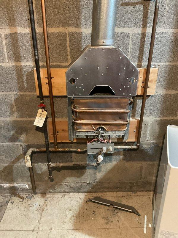 Performed comprehensive tankless water heater flush on Bosch unit located in basement mechanical room. Customer reported decreased water temperature output from the system. Upon inspection, found mineral scale buildup consistent with the home's age and typical hard water conditions in the area affecting heat exchanger efficiency.

Isolated the unit by shutting off gas and water supply valves. Connected descaling pump and circulation hoses to the service valves on both hot and cold water lines. Circulated food-grade descaling solution through the heat exchanger for approximately 45 minutes to dissolve calcium and mineral deposits. Flushed system thoroughly with clean water to remove all descaling solution and loosened sediment. Inspected inline water filter screen and cleaned debris. Tested all gas connections for leaks using soap solution. Verified proper venting integrity on the exhaust system extending through the cinder block wall. Restored water and gas supply, then fired unit to v