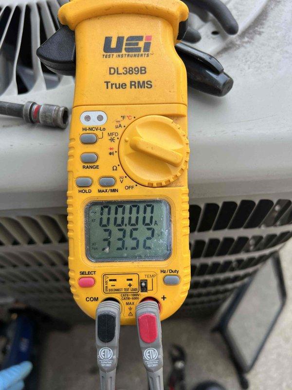 Completed comprehensive Gold AC Inspection on 10-year-old air conditioning system with no reported issues. Performed standard tune-up procedures including electrical testing with multimeter, which showed normal voltage readings at 33.52V. During inspection, identified a horizontal crack in the condensate drain line PVC pipe requiring attention to prevent future water damage or drainage issues.