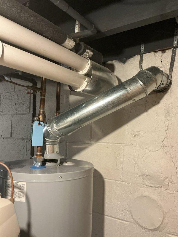 Completed comprehensive Gold AC inspection on residential HVAC system with equipment over 10 years old located in basement. Performed thorough examination of air handler, coil assembly, and associated ductwork including insulated supply lines and metallic distribution components. During inspection, identified significant water heater failure with active leaking at base of unit, resulting in water accumulation on concrete floor with visible staining and potential water damage. Documented all findings including overhead piping infrastructure, copper plumbing connections with shutoff valves, and foam-insulated distribution lines. System operational at time of inspection with single-zone configuration confirmed.