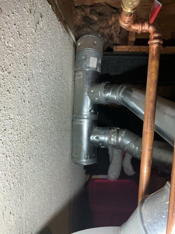 # Tanked Water Heater Service

Responded to a violation correction notice requiring installation of a B-vent T fitting on the water heater exhaust system. Upon arrival, inspected the existing galvanized vent piping configuration and identified the missing B-vent tee component required to bring the installation into compliance with current plumbing and venting codes.

Installed the proper B-vent T fitting into the existing vertical vent pipe system, ensuring secure connections between the water heater flue outlet and the main chimney vent. The B-vent T provides the necessary draft diverter and allows for proper venting of combustion gases while preventing downdrafts. Verified all connections were properly sealed and secured using appropriate fasteners and support brackets.

Confirmed adequate clearances from combustible materials and verified proper pipe support throughout the vertical run. Inspected surrounding copper water supply lines with shut-off valves and insulated piping to ensu