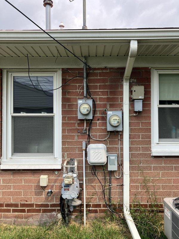 Conducted site assessment for HVAC equipment replacement estimate at residential property with natural gas heating system. Evaluated existing outdoor air conditioning unit located on concrete pad in side yard, along with associated electrical components, meters, and gas service connections mounted on exterior brick wall. Documented current equipment configuration and utility infrastructure to provide comprehensive replacement recommendations.