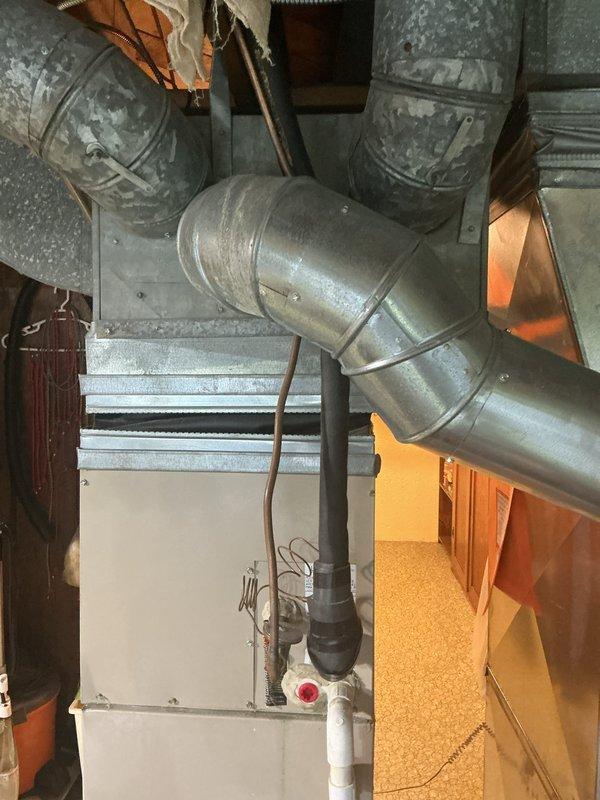 Provided comprehensive replacement estimate for 23-year-old basement-installed HVAC system including air conditioning unit and furnace with undetermined fuel type. Assessed existing equipment configuration showing aged ductwork, weathered metal enclosures, PVC drainage piping, and galvanized supply ducts with visible deterioration throughout the system. Documented current system layout and components to prepare detailed equipment replacement specifications, noting that portions of the existing system are experiencing operational failures.