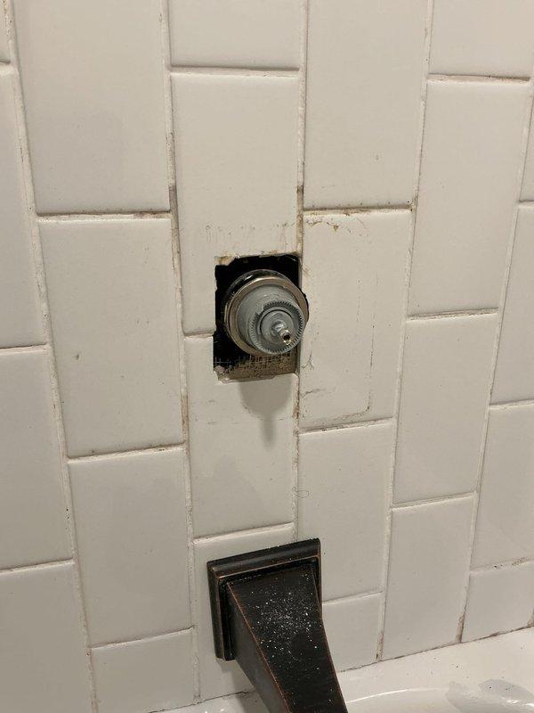 Responded to a bathroom faucet leak that had persisted for five days in a 60-year-old home. Upon arrival, found that the faucet handle had been drilled off by the homeowner in an attempt to stop the leak. Assessed the shower valve assembly mounted in the tiled wall, removed the damaged components, and installed a replacement valve control mechanism to restore proper function and eliminate the water leak.