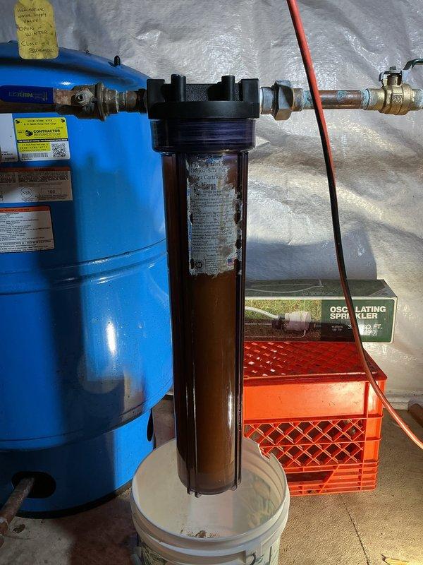 Responded to low water pressure complaint affecting entire residence. Upon inspection of water filtration system in crawl space, confirmed water filter cartridge was cross-threaded in housing, restricting flow throughout plumbing system. Removed improperly installed filter cartridge from transparent housing unit connected to main water line and blue pressure tank assembly. Cleaned housing threads to ensure proper sealing, installed new filter cartridge with correct threading and torque specifications, and verified all connections were secure. Tested system operation and confirmed full water pressure restoration to all fixtures throughout home.