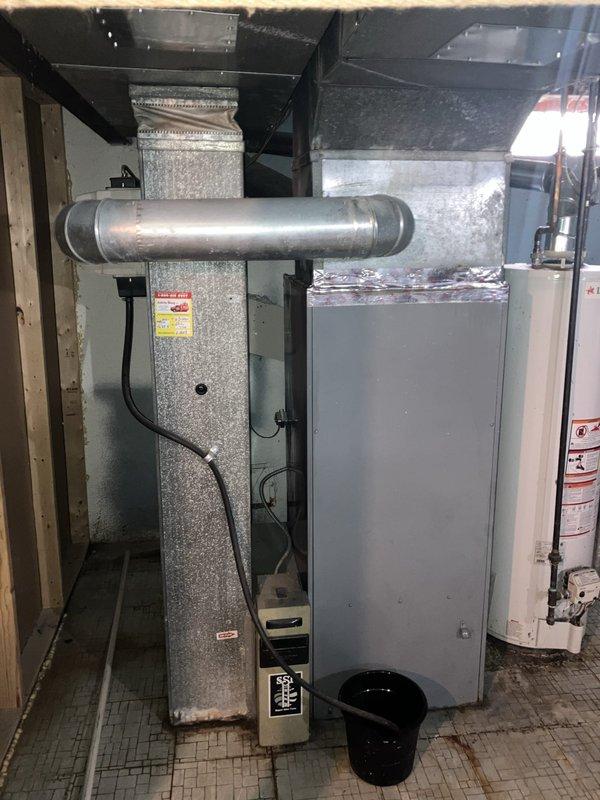 Provided estimate for replacement of existing 1969 furnace and air conditioning system currently located in basement utility area. Existing natural gas furnace and AC unit are operational but nearing end of service life at over 50 years old. Assessed current equipment configuration including ductwork, humidifier control system, and thermostat setup to provide comprehensive replacement options for modern high-efficiency HVAC system.