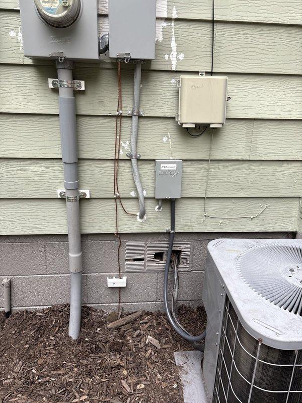 Completed 150 amp electrical service upgrade for residential property. Installed new main electrical panel on interior wall with proper circuit breaker distribution box and secure mounting. Ran new service entrance conductors from exterior meter base through gray PVC conduit system down exterior wall, properly secured with mounting brackets. Upgraded meter base and established new service connection point. Installed exterior junction boxes and weatherproof enclosures to code specifications. Routed all electrical conduits along exterior siding and through foundation penetration to connect with new interior panel. All work performed in compliance with current NEC standards for residential service upgrades. System tested and verified operational upon completion.