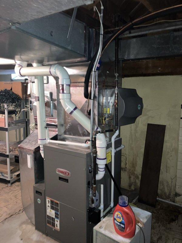 Performed comprehensive leak test on 15-year-old residential air conditioning system located in basement following previous refrigerant recharge requirement. Inspected Lennox air handler unit, refrigerant lines, brass valve assembly, and associated copper tubing for potential leak points. Evaluated system components including condensate drainage configuration with PVC piping, electrical connections, and refrigerant line insulation integrity to identify source of refrigerant loss and determine viability of repair versus replacement recommendation.