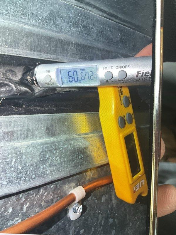 Responded to no cooling complaint on 2016 central air conditioning system. Upon arrival, confirmed unit was blowing warm air with inadequate temperature differential. Performed diagnostic temperature measurements at supply ductwork, recording wet bulb and dry bulb readings to assess system performance. Supply air temperature measured at 60.52°F WB and 50.5°F, indicating insufficient cooling capacity. Inspected outdoor condensing unit and refrigerant lines. Observed significant dust accumulation on ductwork and system components. Diagnostic testing completed to identify root cause of cooling failure.