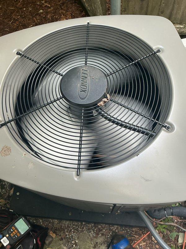 Completed comprehensive Gold AC Inspection on a 10-year-old Lennox air conditioning system with outdoor condensing unit located in basement area. Performed thorough examination of condensing unit, noting significant weathering, dirt accumulation, and organic growth on exterior casing and components. Inspected fan assembly with protective wire guard, verified electrical disconnect box mounting and connections, examined refrigerant line connections, and assessed overall unit operation. Documented unit condition showing age-related wear consistent with outdoor exposure, including surface deterioration and debris accumulation around base. All major components inspected and system operational status verified per Gold maintenance protocol specifications.