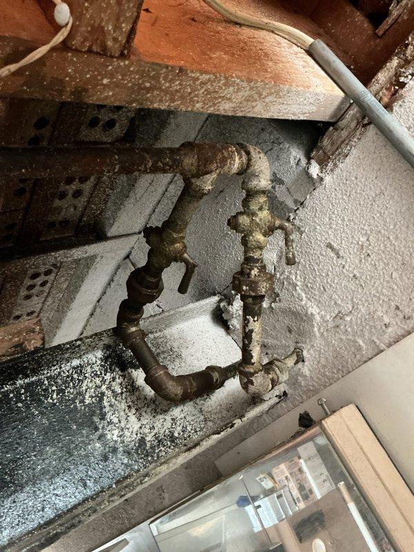 Responded to service call regarding strange noises coming from gas fireplace when flame is activated. Performed comprehensive inspection of gas line routing from main supply to fireplace unit. Examined corroded gas piping and valve assembly at basement connection point, noting significant age-related deterioration of metal components and fittings. Inspected fireplace unit interior compartment and burner assembly, identifying accumulated debris and degraded insulation material within firebox. Conducted pressure testing and leak detection on gas line connections. Documented existing conditions of aged infrastructure with photographic evidence for homeowner records.