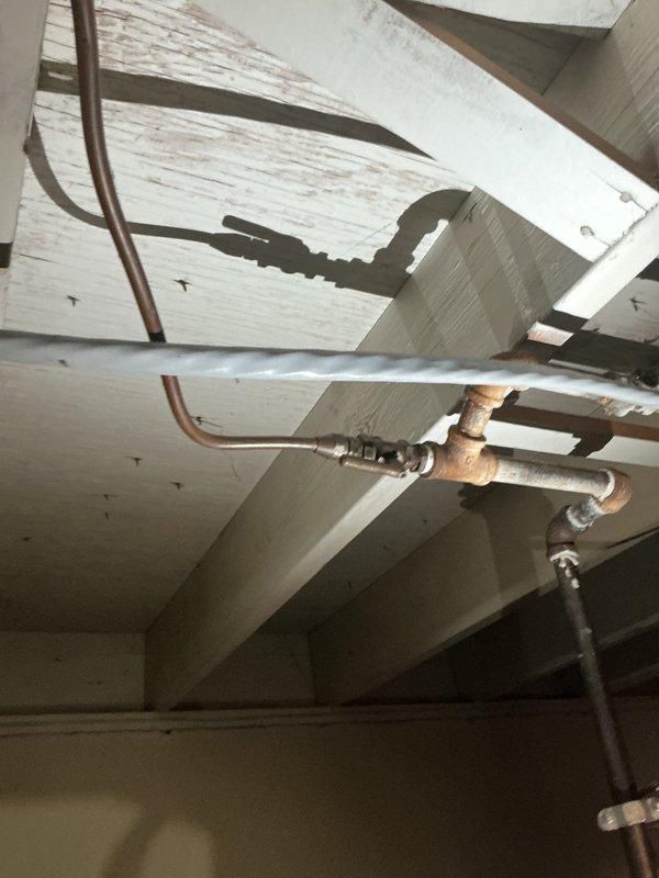 Responded to service call for non-functioning gas dryer following utility company recommendation for gas line repair. Upon inspection of basement utility area, assessed gas supply piping system serving laundry appliances. Examined existing gas line infrastructure including aged galvanized piping showing visible corrosion and discoloration along ceiling-mounted runs. Evaluated copper tubing connections and fittings in exposed crawl space area with deteriorating conditions. Performed necessary repairs to restore proper gas supply to dryer appliance, ensuring all connections met code requirements and passed leak testing protocols.