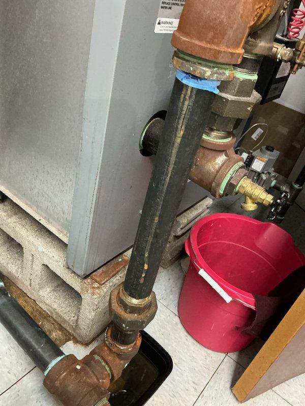 Replaced deteriorated black iron piping assembly showing severe corrosion and oxidation. The existing vertical pipe section and threaded fittings exhibited heavy rust buildup and structural degradation, posing a leak risk. Installed new black pipe with proper threaded connections and brass fittings to restore system integrity and prevent future water damage.