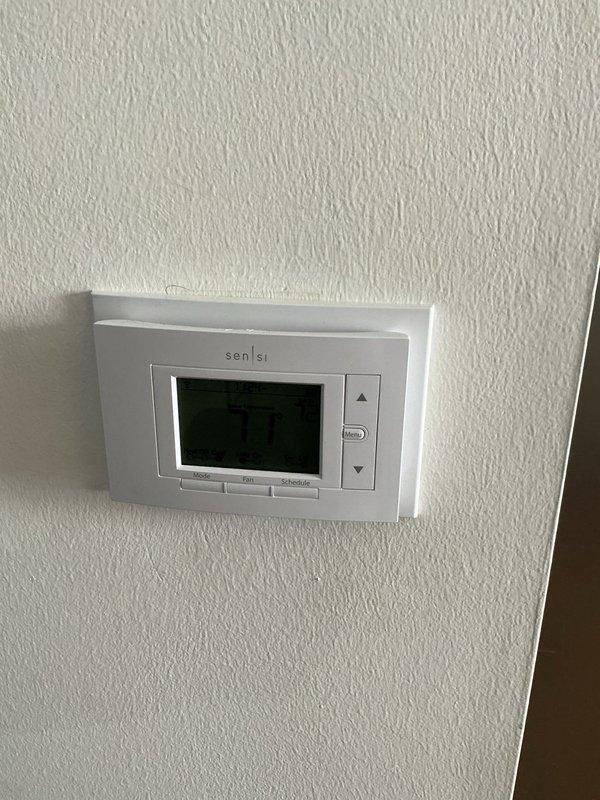 Performed comprehensive Gold AC inspection on 10+ year old air conditioning system located in basement. Evaluated existing HVAC equipment including condensate drainage system with PVC piping and assessed overall system condition. Documented current thermostat (Sensi digital programmable unit set at 70°F) and photographed equipment configuration for replacement estimate preparation.