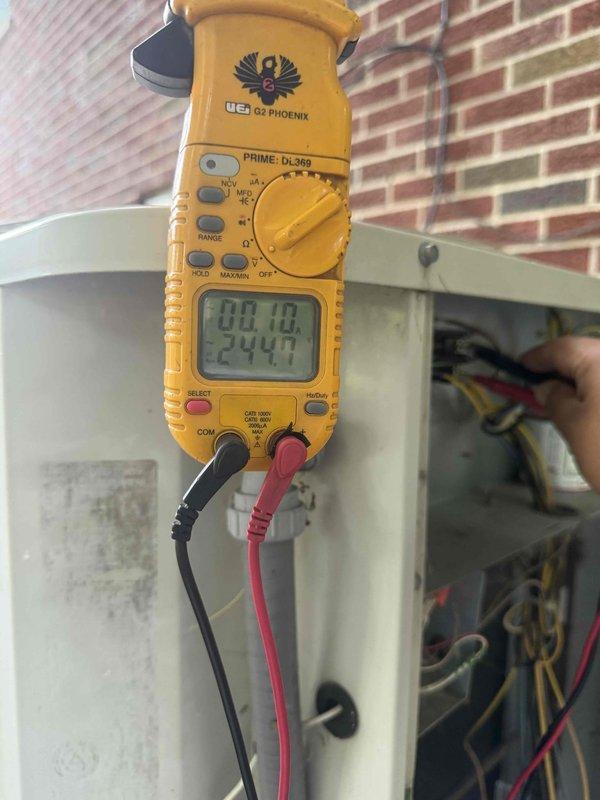 Completed comprehensive Gold AC Inspection on 20-year-old residential air conditioning system with evaporator coil located in basement and condenser unit positioned outdoors. Performed electrical diagnostics using digital clamp meter, recording voltage and amperage readings at the outdoor unit to verify proper system operation and component functionality. Conducted thorough visual inspection of condenser unit exterior, coil condition through protective grille, and internal wiring connections to assess overall system health and identify any maintenance concerns associated with the aging equipment.