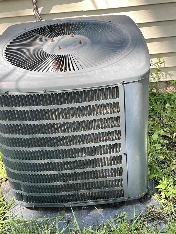 Responded to no cooling complaint on 10-year-old residential air conditioning system. Upon arrival, performed diagnostic evaluation of outdoor condenser unit located in backyard. Unit was running but failing to produce cold air. Conducted visual inspection of condenser coils, fan operation, and overall unit condition, noting age-related wear on exterior components. Utilized digital multimeter to test electrical components and verify proper voltage and amperage readings throughout the system. Measurements indicated potential refrigerant or compressor-related issue affecting cooling capacity. Documented equipment condition with photographs showing weathered condenser unit with horizontal coil fins and cylindrical fan assembly. Provided customer with diagnostic findings and recommended next steps for repair or replacement consideration given the system's age and current performance issues.
