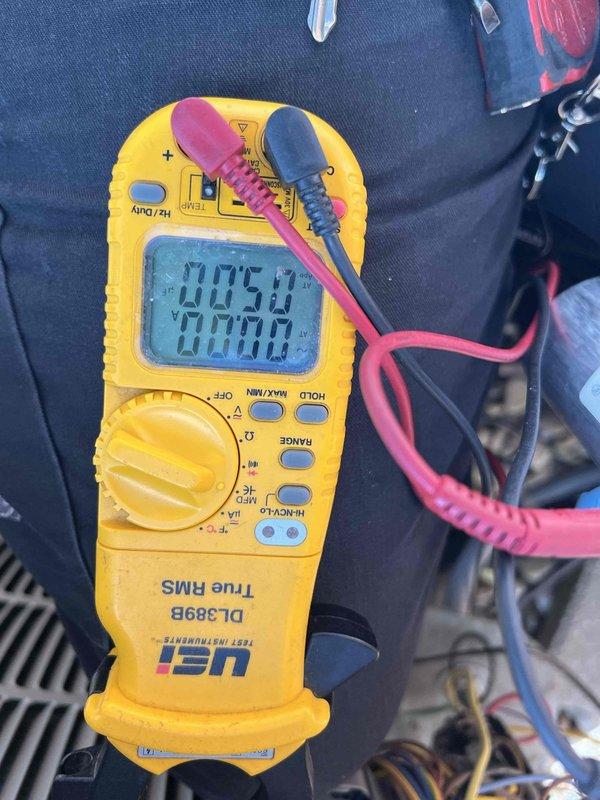 Completed non-service plan AC inspection on 12-year-old basement air conditioning system with coil assembly. Performed comprehensive system diagnostics using digital multimeter to verify electrical parameters and measured capacitance readings at 32.33 μF to assess capacitor condition. System confirmed operational at time of inspection with photographic documentation of testing procedures and equipment readings.