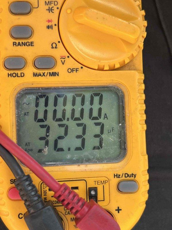 Completed non-service plan AC inspection on 12-year-old basement air conditioning system with coil assembly. Performed comprehensive system diagnostics using digital multimeter to verify electrical parameters and measured capacitance readings at 32.33 μF to assess capacitor condition. System confirmed operational at time of inspection with photographic documentation of testing procedures and equipment readings.