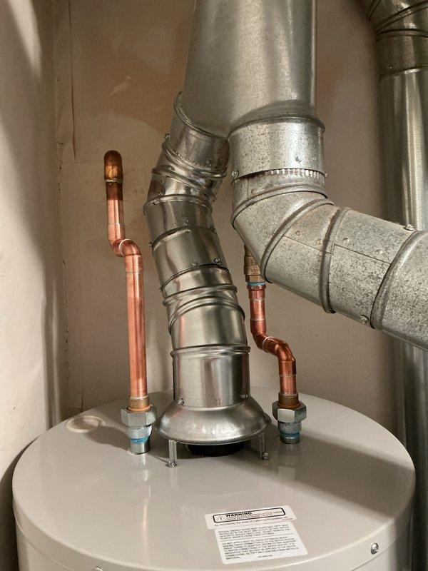 Installed a 40-gallon Bradford White tanked water heater in the utility area. Connected copper supply lines with compression fittings to the inlet and outlet ports, installed proper venting using galvanized ductwork with elbow configuration, and secured all pipes and ducts with metal clamps per manufacturer specifications.
