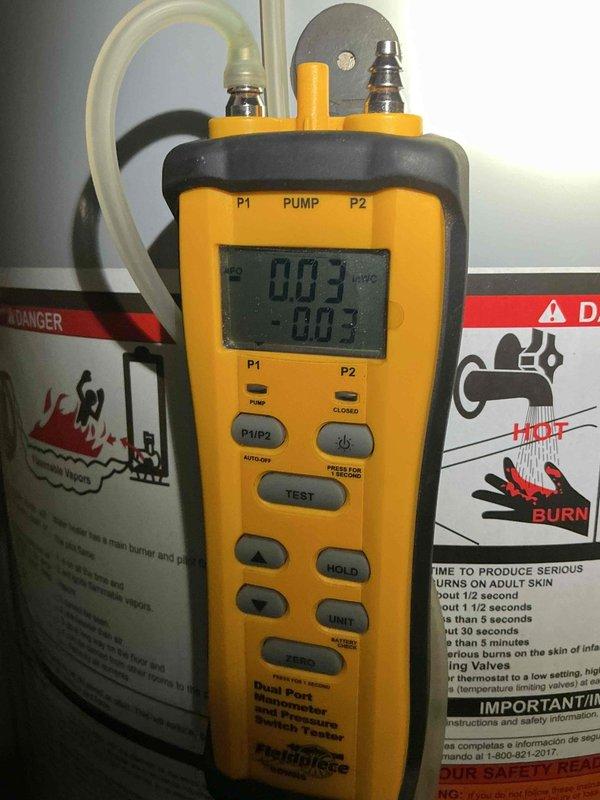 Performed draft test on 2024 model hot water heater located in bedroom closet. Utilized digital pressure measurement device to conduct diagnostic testing on the unit, with readings indicating proper pressure levels at 003 PSI on both P1 and P2 gauges. Inspected vent pipe assembly and noted visible deterioration on the metal flue pipe surface with peeling material present on the middle section. Verified proper venting connection from water heater top through insulated enclosure, though vent pipe showed signs of aging and surface corrosion requiring monitoring for future replacement consideration.