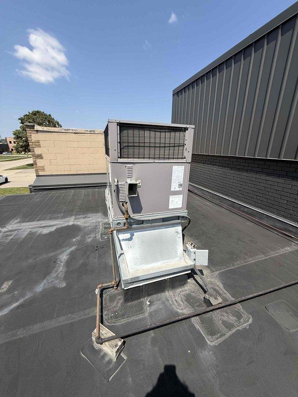 Responded to commercial property for multiple AC leak complaints affecting office space. Accessed rooftop unit via ladder and inspected packaged RTU condenser, identifying compromised condensate drainage system with visible water staining on roof membrane beneath unit. Examined refrigerant line insulation showing weathering and deterioration. Inspected mini split system located adjacent to property for reported leaking condition. Assessed garage thermostat malfunction. Documented equipment conditions with photographic evidence showing rooftop HVAC installation, condensate pan assembly, copper refrigerant lines with worn insulation, and roof membrane water damage patterns.