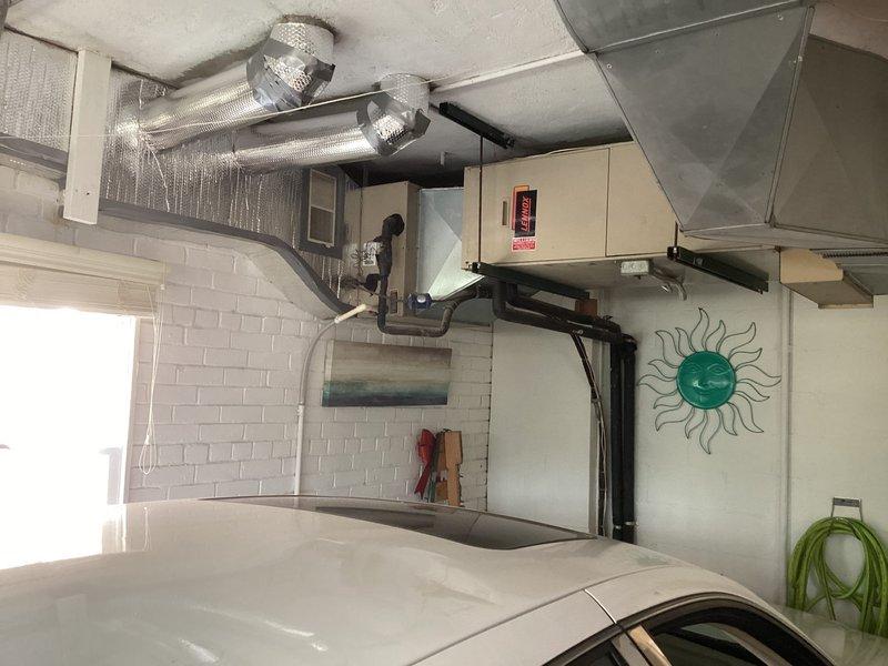 Responded to service call for 15-year-old Unico system located in basement with reported water accumulation at bottom of tank. Upon arrival, inspected garage-mounted air handler unit and associated ductwork system. Observed extensive HVAC installation with silver insulated flexible ductwork, rigid metal ducts, and wall-mounted beige air handler with control panel. Photographed equipment configuration and installation for diagnostic purposes. Customer requested specific technician for follow-up evaluation and potential valve replacement to address condensate drainage issue. Appointment requires rescheduling to accommodate technician availability and complete necessary repairs to resolve water accumulation problem.
