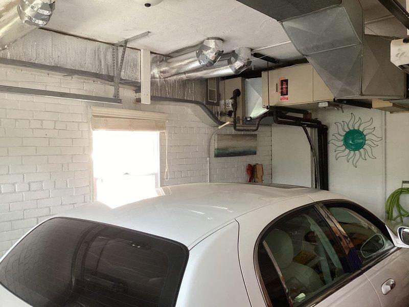 Responded to service call for 15-year-old Unico system located in basement with reported water accumulation at bottom of tank. Upon arrival, inspected garage-mounted air handler unit and associated ductwork system. Observed extensive HVAC installation with silver insulated flexible ductwork, rigid metal ducts, and wall-mounted beige air handler with control panel. Photographed equipment configuration and installation for diagnostic purposes. Customer requested specific technician for follow-up evaluation and potential valve replacement to address condensate drainage issue. Appointment requires rescheduling to accommodate technician availability and complete necessary repairs to resolve water accumulation problem.