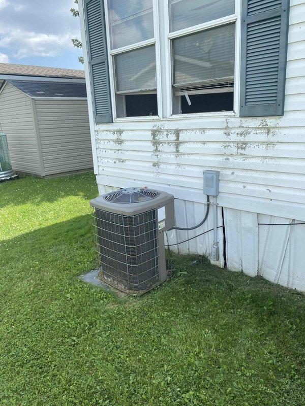 Performed estimate for complete furnace replacement in 1999 mobile home with 27-year-old heating system located in laundry room utility closet. Assessed existing HVAC equipment configuration including aged blower assembly, furnace components, and electrical connections showing significant wear and dust accumulation in vertically-stacked installation. Documented current system condition, exterior condensing unit on concrete pad, and discussed financing pre-qualification options with homeowner for upcoming replacement project.