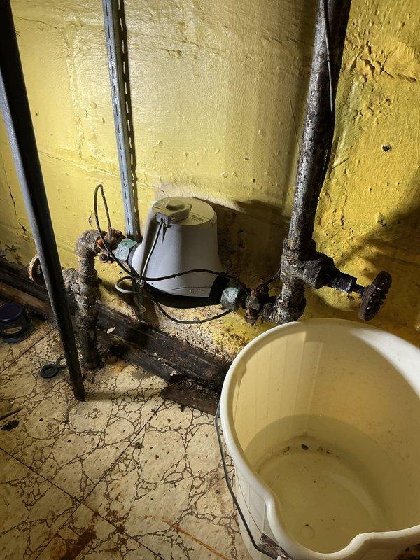 Responded to service call for corroded main water shutoff valve preventing proper water isolation to the residence. Upon inspection, discovered heavily corroded gate valve and associated piping in basement utility area showing extensive oxidation and deterioration. Valve mechanism seized due to corrosion, rendering it inoperable and creating potential emergency situation where water supply cannot be shut off in case of plumbing failure. Documented existing conditions including rusted support brackets, degraded floor surfaces, and aging plumbing infrastructure. Advised homeowner that main shutoff valve requires replacement to restore proper water control functionality and prevent potential water damage from inability to isolate water supply during emergency situations.