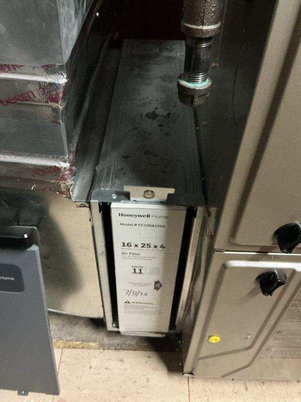 Completed comprehensive NSP AC inspection on 3-year-old residential air conditioning system located in basement. Verified unit operational status with homeowner present. Inspected indoor air handler assembly including Honeywell Home FC100A1029 air filter unit (16x25x4, MERV 11 rating) installed in metal ductwork system. Examined control panel display and verified proper function. Assessed outdoor condenser unit positioned on exterior mulch bed adjacent to brick structure. Inspected condenser fan operation, protective grille, and exterior casing condition. Checked electrical conduit and wiring connections at exterior installation. System operating within normal parameters with no deficiencies noted at time of inspection.