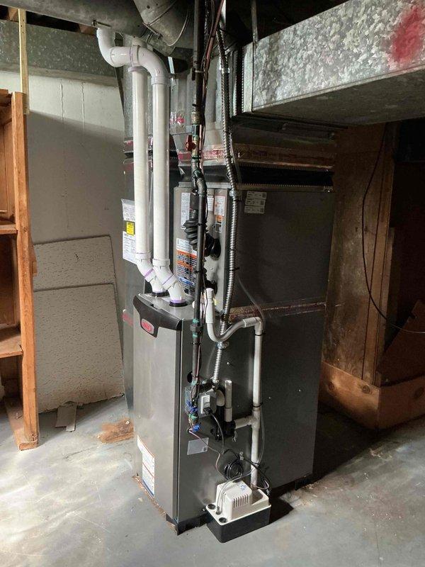 Completed full HVAC system installation including a 70,000 BTU furnace and 2-ton air conditioning unit in basement mechanical room. Addressed height clearance issue during installation requiring remeasurement and adjustment of equipment placement. Installed complete venting system with white PVC piping routed vertically through basement and exterior wall termination, connected all ductwork including flexible black ducting to furnace plenum, and reconnected existing electrical components. Obtained mechanical permit and registered system for utility rebate program under AHRI certificate 215663144.