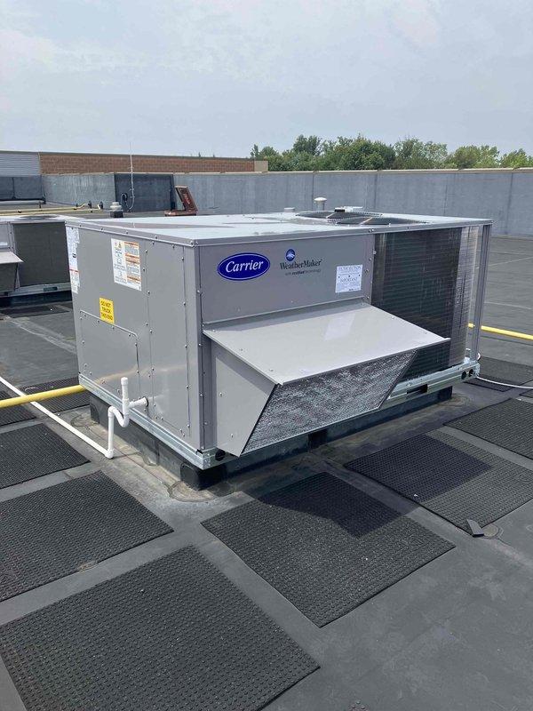 Completed like-for-like replacement of 7.5 ton Carrier rooftop unit on commercial building using 28-ton crane for equipment delivery, positioning, and haul-away of existing unit. Installed new RTU on weatherstripped curb adapter with rubber isolation pads, updated gas valve, replaced thermostat with White-Rodgers 1F95-0680 model, installed economizer for energy efficiency, utilized existing electrical disconnect, and performed complete system startup including heat exchanger burn-off and operational verification.