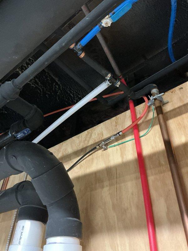 Installed water-powered backup sump pump system with RPZ (Reduced Pressure Zone) backflow preventer in basement utility area. The installation included routing white PVC discharge piping vertically from floor level, connecting to existing plumbing infrastructure, and ensuring proper integration with the home's water supply system to provide automatic backup pumping capability during primary pump failure or power outages.