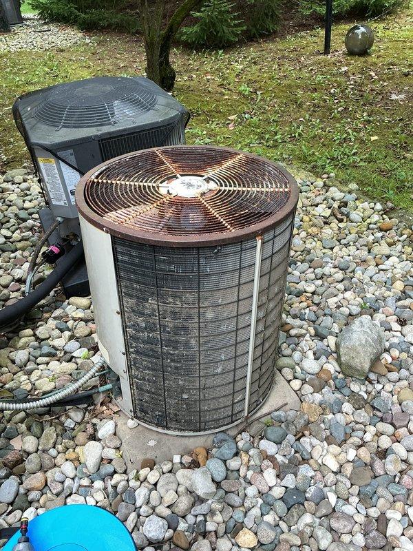 Responded to no-cooling complaint on residential central air conditioning system. Upon arrival, found outdoor condenser unit with significant weathering and age-related deterioration. Inspected dual condenser setup with primary unit showing extensive rust and oxidation on copper-colored top grille, indicating prolonged exposure to elements. Evaluated electrical connections, refrigerant lines, and overall system operation. Documented equipment condition showing compromised components and aging infrastructure requiring attention to restore cooling capacity.