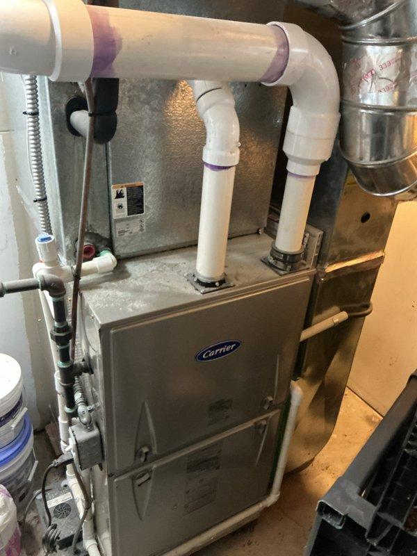 Responded to no cooling complaint on 25-year-old Carrier air conditioning system with evaporator coil connected to basement furnace. Upon arrival, found thermostat displaying 80 degrees and system not maintaining setpoint. Performed diagnostic evaluation of complete HVAC system including furnace cabinet, refrigerant lines, condensate drainage, and thermostat operation. Documented existing equipment conditions through photographic records showing Carrier furnace unit with PVC venting, associated ductwork, and Honeywell digital thermostat. Due to advanced age of equipment exceeding typical service life expectancy, provided homeowner with assessment of system condition and recommended replacement options for reliable cooling performance.